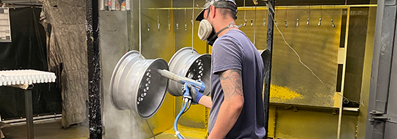 Alloy wheels being powder coated by a powder coater